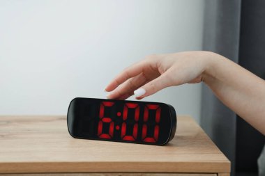Kadın, başucundaki masanın dijital alarmını kapatıyor.