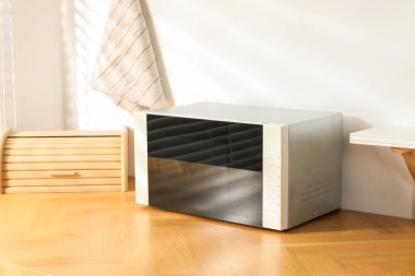 Kapalı mikrodalga fırın ve ekmek kutusu ahşap masa içinde.