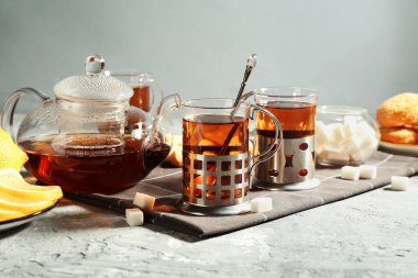 Gri dokulu masada servis edilen metal tutacaklı çay bardakları.