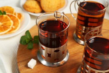 Beyaz ahşap masada servis edilen metal tutacaklı çay bardakları.