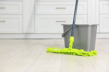 İçerideki ahşap zeminde mikrofiber paspas ve kova. Metin için boşluk