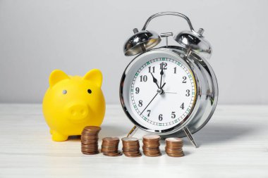 Alarm saati, bozuk paralar ve beyaz ahşap masada kumbaralar. Vergi zamanı