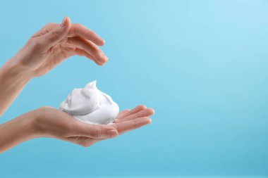 Açık mavi arka planda kozmetik köpüklü kadın, metin için yeri olan yakın plan