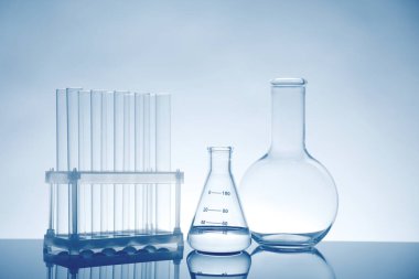 Ayna yüzeyinde ışık arkaplanına karşı sıvı bulunan laboratuvar camları