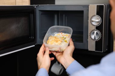 Yemek kabını mikrodalgaya koyan adam, yakın plan.