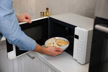 Yemek tabağını mikrodalgaya koyan adam, yakın plan.