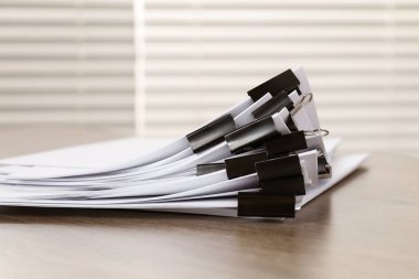 Kapalı alanda, ahşap masa üzerinde kağıt kağıtları olan ataçlar.