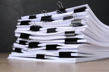 Koyu arkaplan ile ahşap masa üzerinde kağıt sayfaları ile cilt klipsleri, yakın çekim