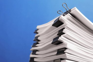 Mavi arkaplandaki kağıtların olduğu ataçlar, yakın plan. Metin için boşluk