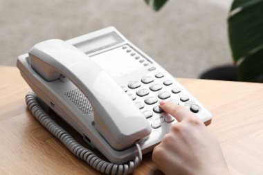 Kapalı alandaki ahşap masada telefonla arayan kadın.