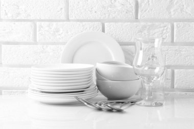 Different clean dishware on white table near brick wall