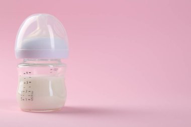 Pembe arka planda sütle beslenme şişesi, metin için boşluk