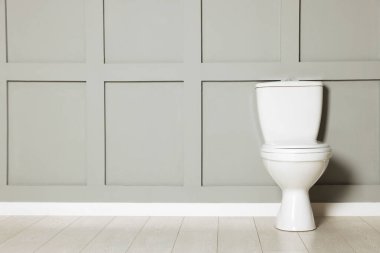 Gri duvarın yanındaki seramik klozet.