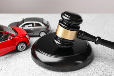 Motorlu taşıt kazası yasası. Gavel ve araba modelleri gri arkaplanda, yakın plan
