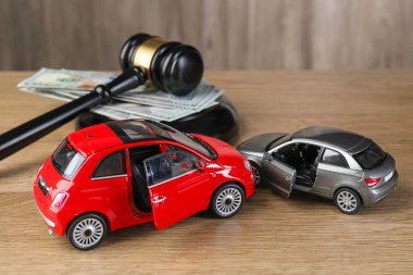 Motorlu taşıt kazası yasası. Gavel, para ve araba modelleri ahşap arka planda, yakın plan.
