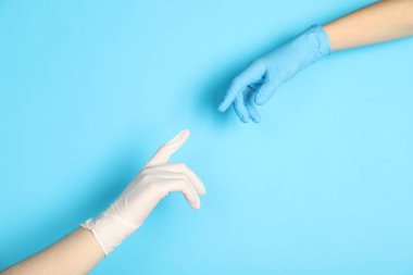 Tıbbi eldivenli doktorlar açık mavi arka planda parmaklarına dokunuyor, yakın plan.
