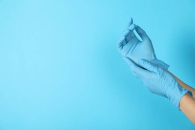 Doktor açık mavi arka plana tıbbi eldiven takıyor, yakın plan. Metin için boşluk