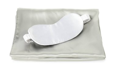 Beyaz arka planda ipek çarşaflar ve uyku maskesi.