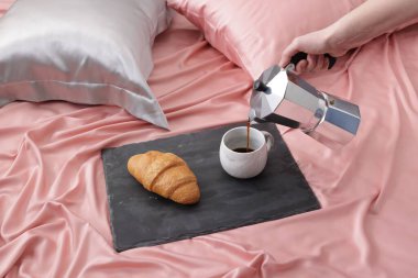 Yatağın üzerine güzel ipek çarşaflarla aromatik kahve koyan kadın, yakın plan.