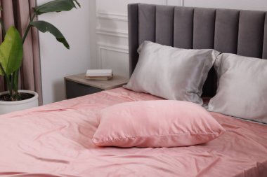 Evde ipek çarşaflı bir yatak.