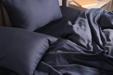 Güzel koyu mavi ipek çarşaflar yatakta, yakın plan.