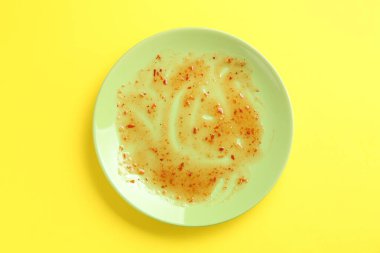 Sarı arka planda kirli bir tabak, üst manzara.