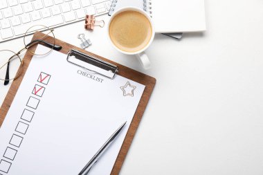 İşaretli kutular, kırtasiye malzemeleri, bardaklar, kahve ve bilgisayar klavyesi olan kontrol listesi beyaz masada, düz konumda. Metin için boşluk