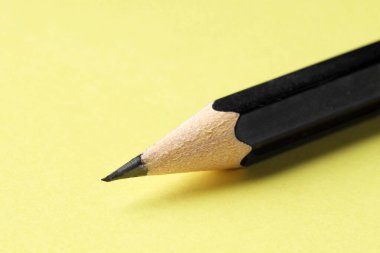 Sarı arka planda keskin bir grafit kalem, yakın plan. Metin için boşluk