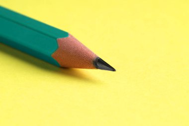 Sarı arka planda keskin bir grafit kalem, yakın plan.