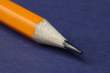 Mavi arkaplanda keskin bir grafit kalem, yakın plan.