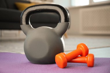 Kettlebell ve dambıllar evdeki spor minderinde.