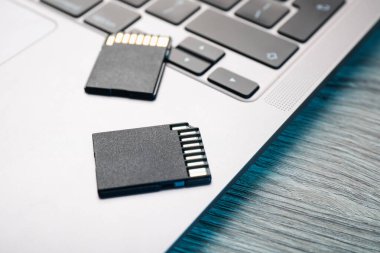 SD hafıza kartları ve dizüstü bilgisayarlar ahşap masada, yakın plan.