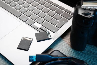 USB kablo, SD hafıza kartları, kamera ve dizüstü bilgisayar ahşap masa, yakın plan