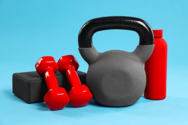 Açık mavi arka planda Kettlebell ve diğer spor ekipmanları