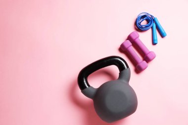 Kettlebell, atlama ipi ve pembe arka planda dambıllar, düz yatış. Metin için boşluk