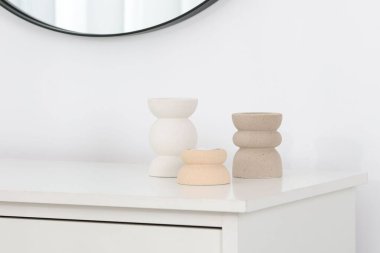 Beyaz dolapta mumları olan şık şamdanlar.