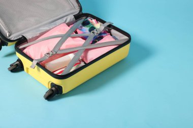 Açık mavi arkaplanda giysiler ve diğer eşyaların olduğu bavul, metin için boşluk