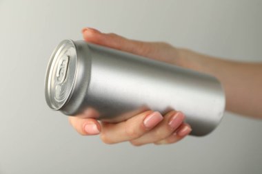 Açık gri arka planda teneke kutusu olan kadın, yakın plan.