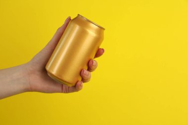 Sarı arka planda teneke kutusu olan kadın, yakın plan. Metin için boşluk