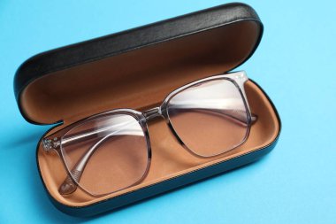 Açık mavi arka planda şık gözlüklü çanta, yakın plan