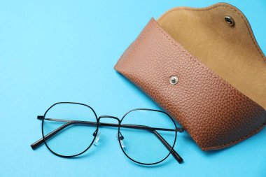 Açık mavi arka planda şık gözlüklü çanta, düz uzanma