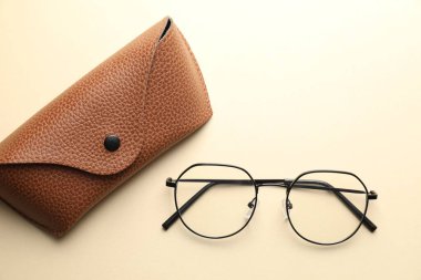 Bej arka planda şık gözlüklü çanta, düz yatış