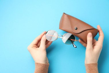 Güneş gözlüklü ve açık mavi arka planda çantası olan bir kadın. Metin için boşluk