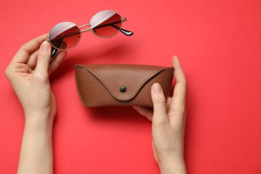 Güneş gözlüklü kadın ve kırmızı arka planda çanta, üst görünüm