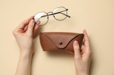 Gözlüklü ve çantalı kadın bej arka planda, üst manzara