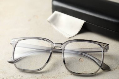 Şık gözlükler ve çanta ışıklı masada, yakın plan.