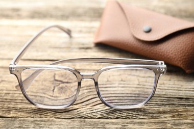 Şık gözlükler ve çanta ahşap masada, yakın plan.
