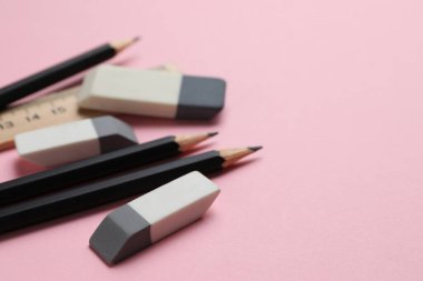 Silgi, cetvel ve pembe arka planda kalemler, yakın plan. Metin için boşluk