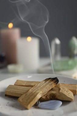 Yanan palo santo sopası ve değerli taşlar masada, yakın plan.