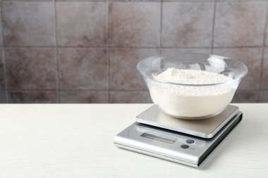 Elektronik mutfak terazisi, beyaz ahşap masa üzerinde un kasesi fayanslı duvar, metin için boşluk